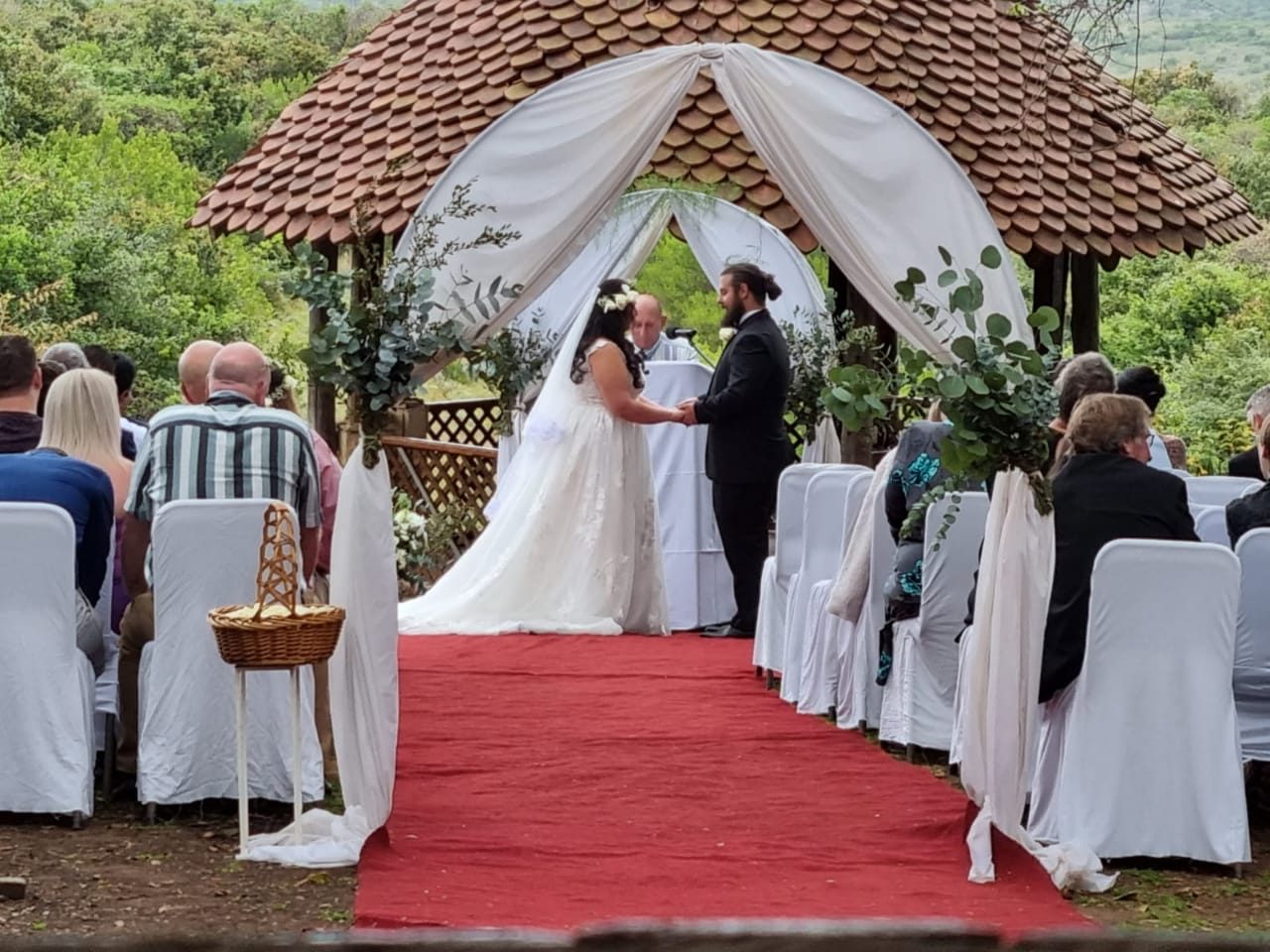 The open-air chapel set among trees in the reserve gardens, chairs in white covers.