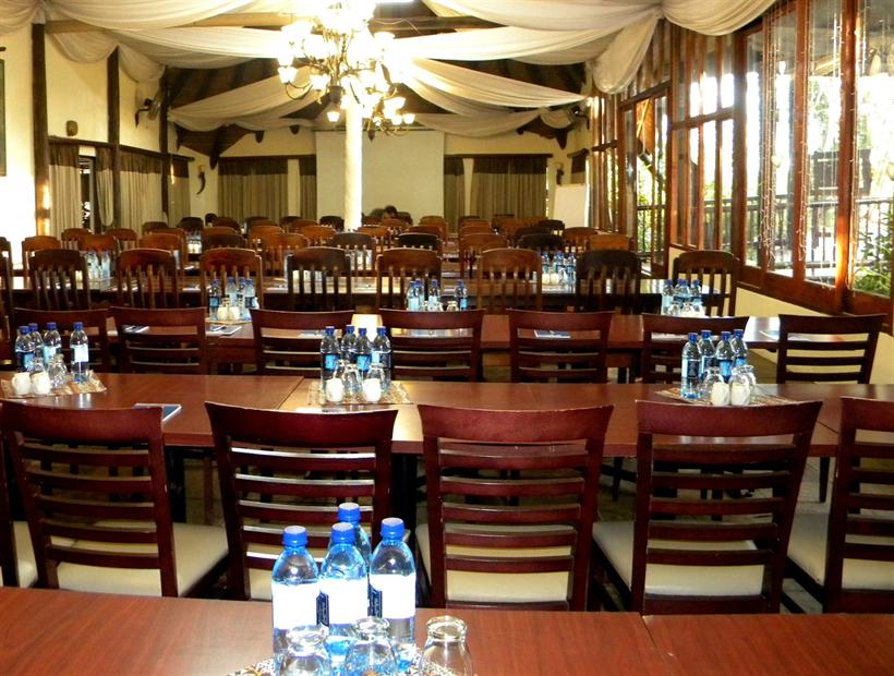 Emthombeni set for a conference: long hardwood tables, draped ceiling, chandeliers, garden windows.